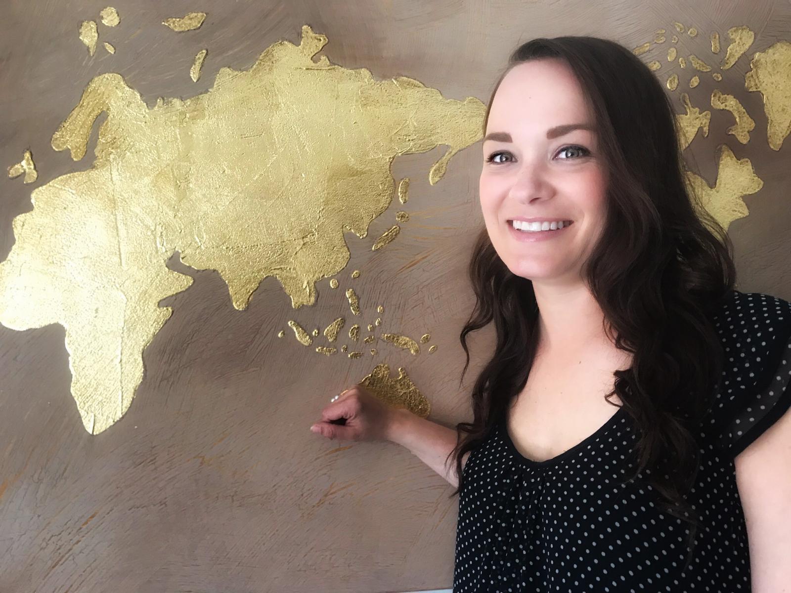  Isabelle Baril souriant devant un mur avec les continents peints dessus 