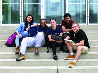 Des étudiants de l'Université Laurentienne assis sur les marches de I'Édifice R.D.-Parker.