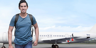 Un étudiant international marchant avec un avion derrière lui 