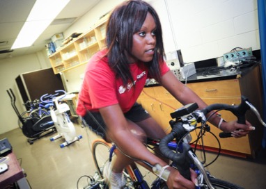 A woman riding a spin bike in a research lab.