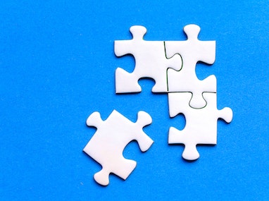 Quatre pièces de puzzle blanches sur fond bleu, avec trois assemblées.