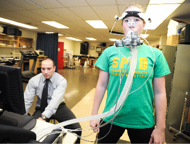 Un chercheur sur un ordinateur et une femme avec un équipement de surveillance de la respiration sur le visage.