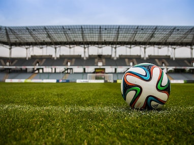 Un ballon de football sur un terrain avec un stade en arrière-plan.