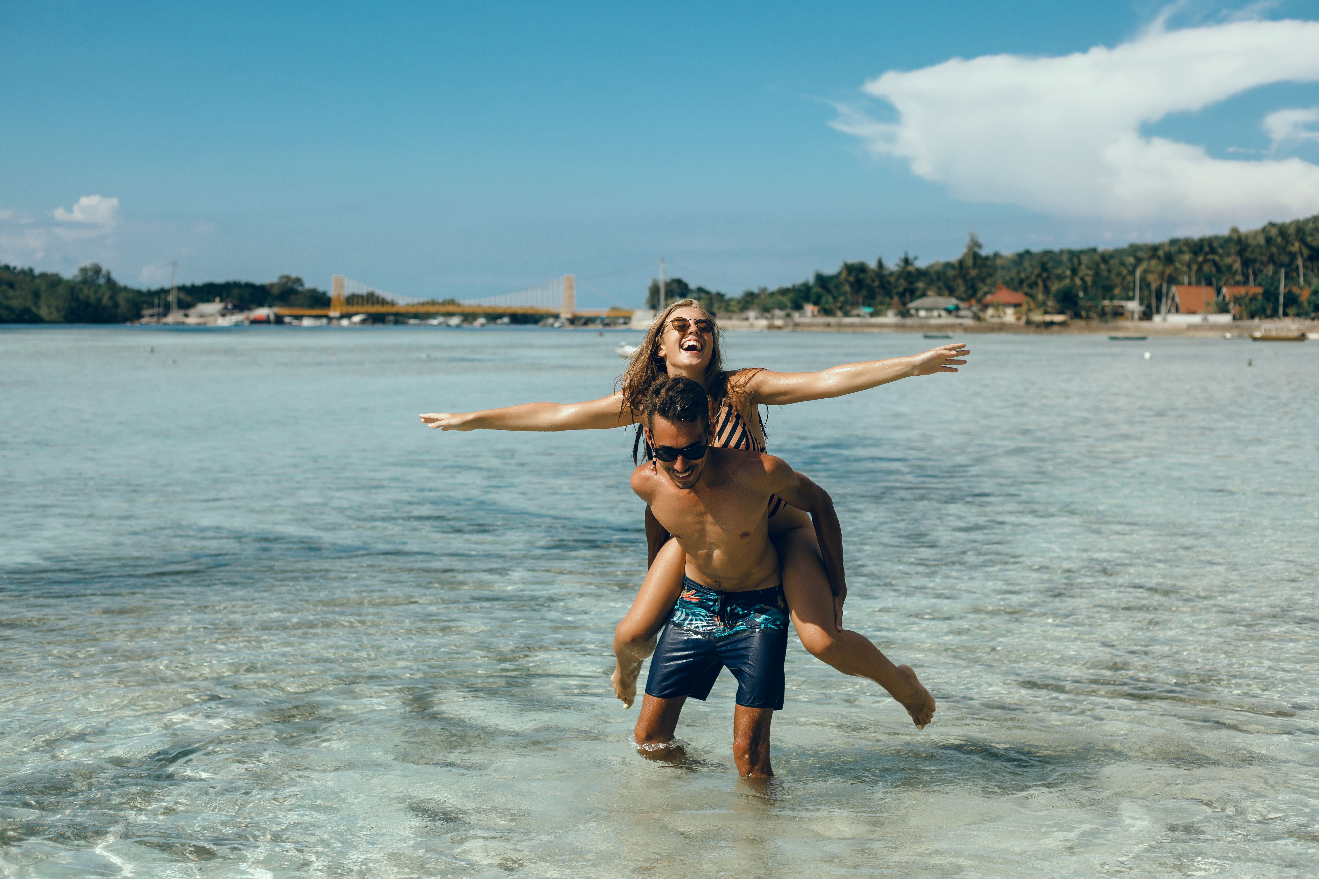 Homme et femme qui jouent à la plage. La femme est sur le dos de l'homme