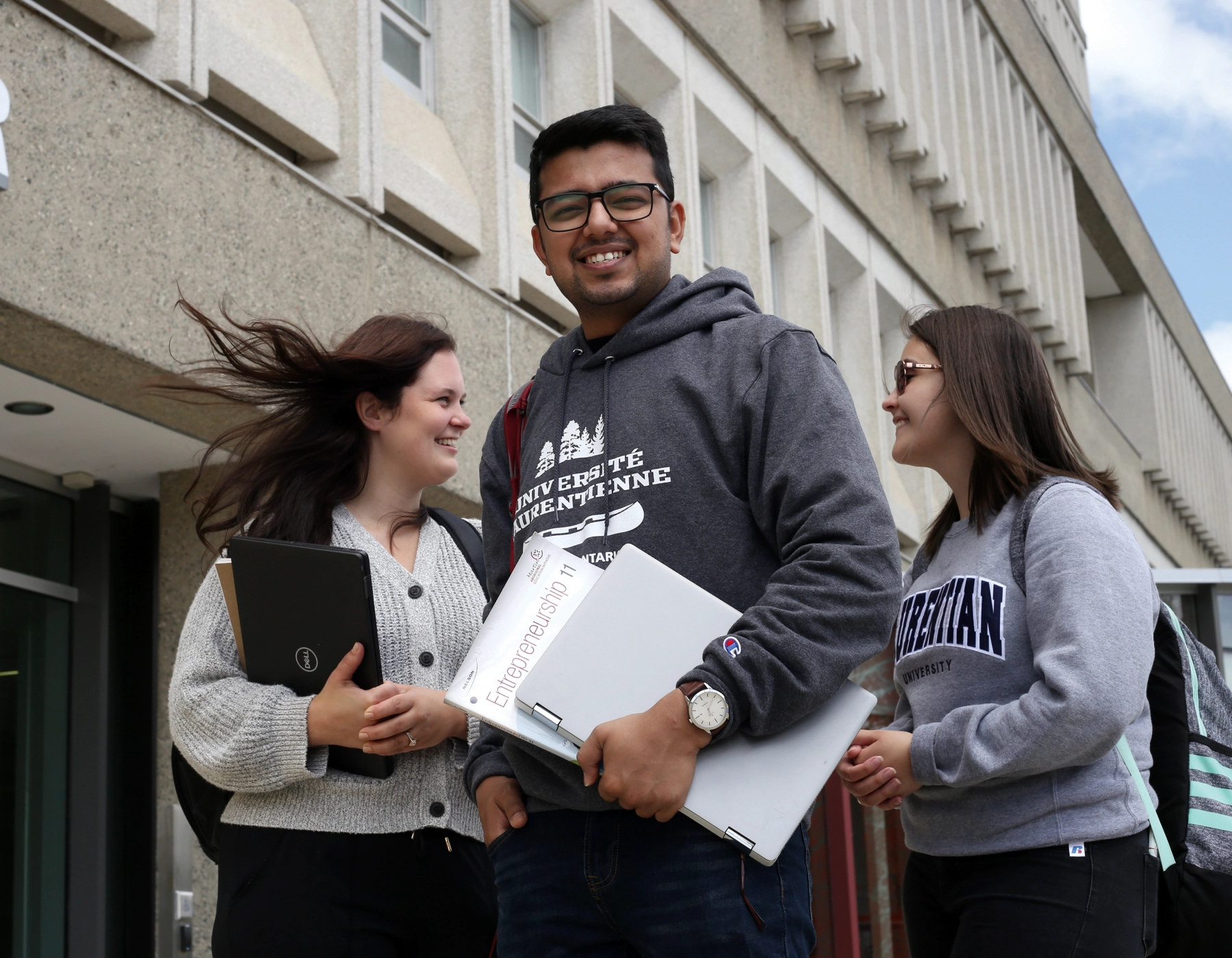 Des étudiants souriant et discutant devant l’édifice R.D.-Parker de l'Université Laurentienne.