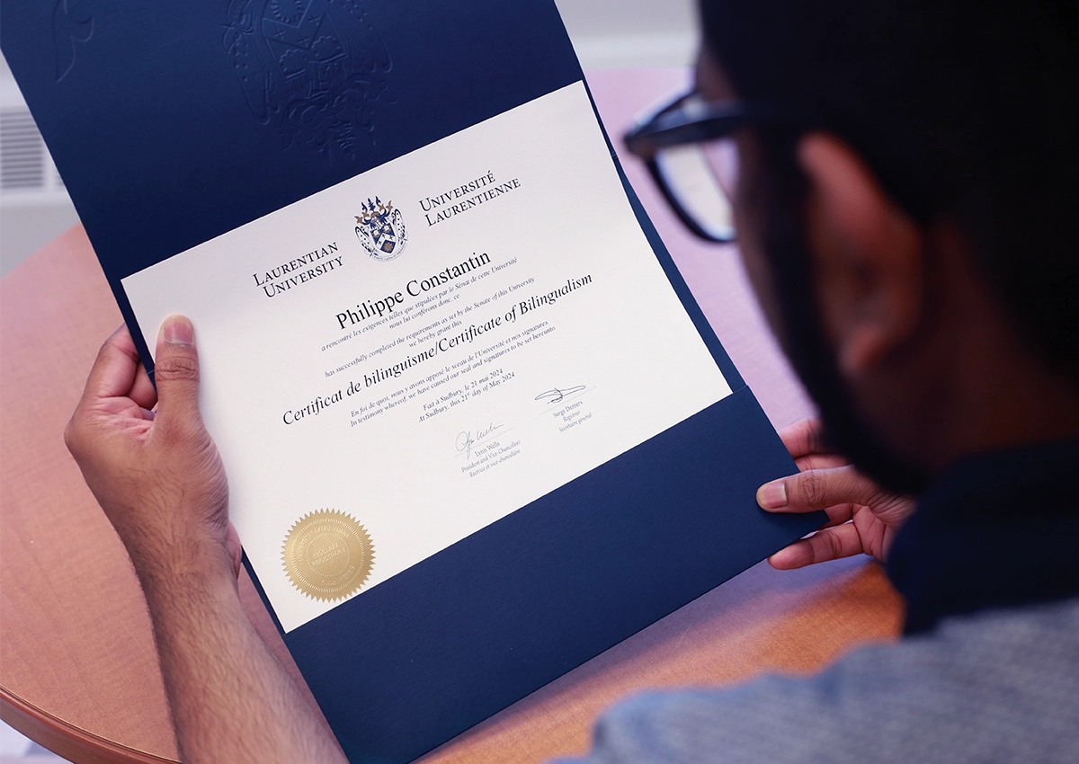 Une étudiante bilingue de l'Université Laurentienne tenant son Certificat de bilinguisme.