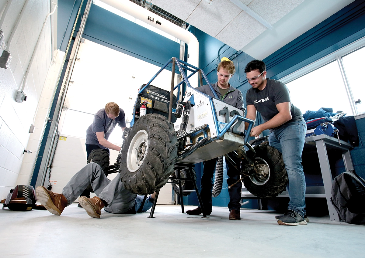 Quatre étudiants de l'Université Laurentienne de l'École de génie Bharti travaillant sur une voiture robotisée.