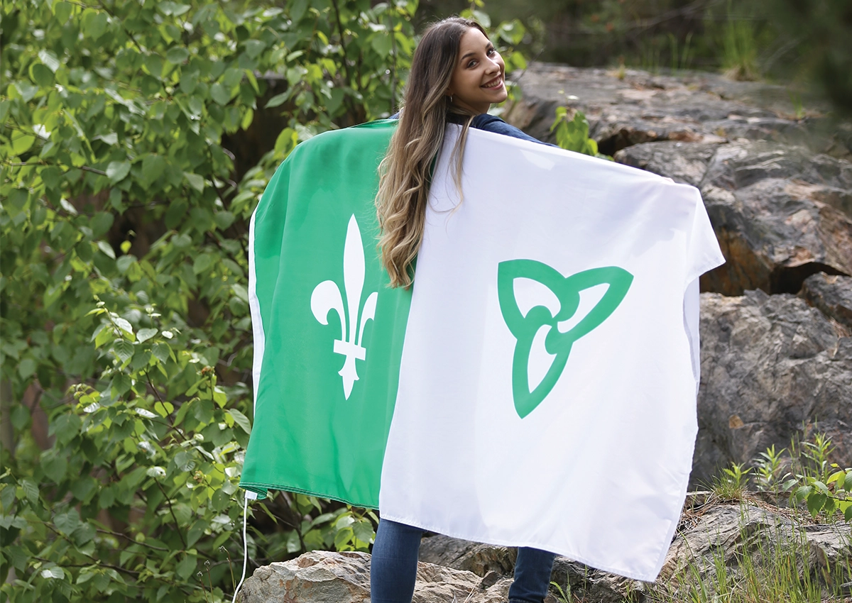 Une étudiante francophone de l'Université Laurentienne portant un drapeau franco-ontarien sur son dos.