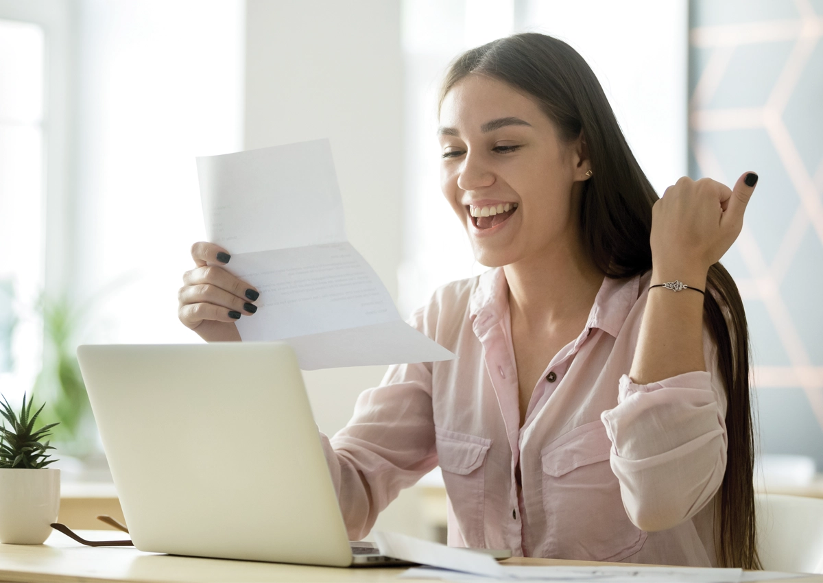 Young woman smiling at her acceptance letter.