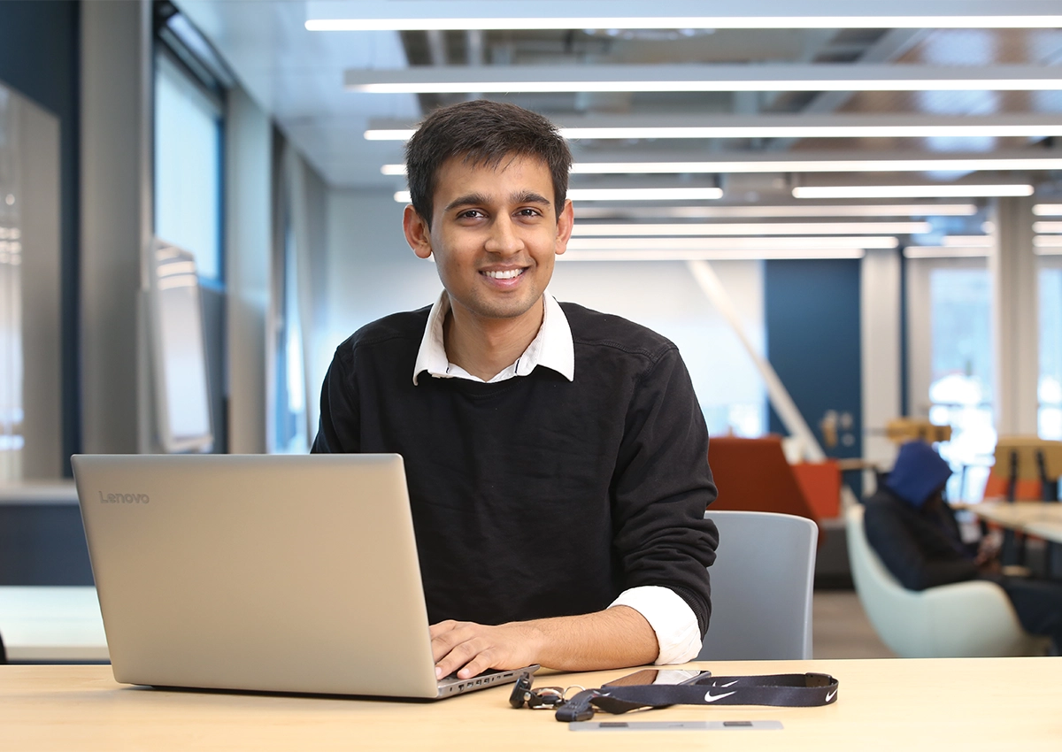 Étudiant assis à son bureau avec un ordinateur portable