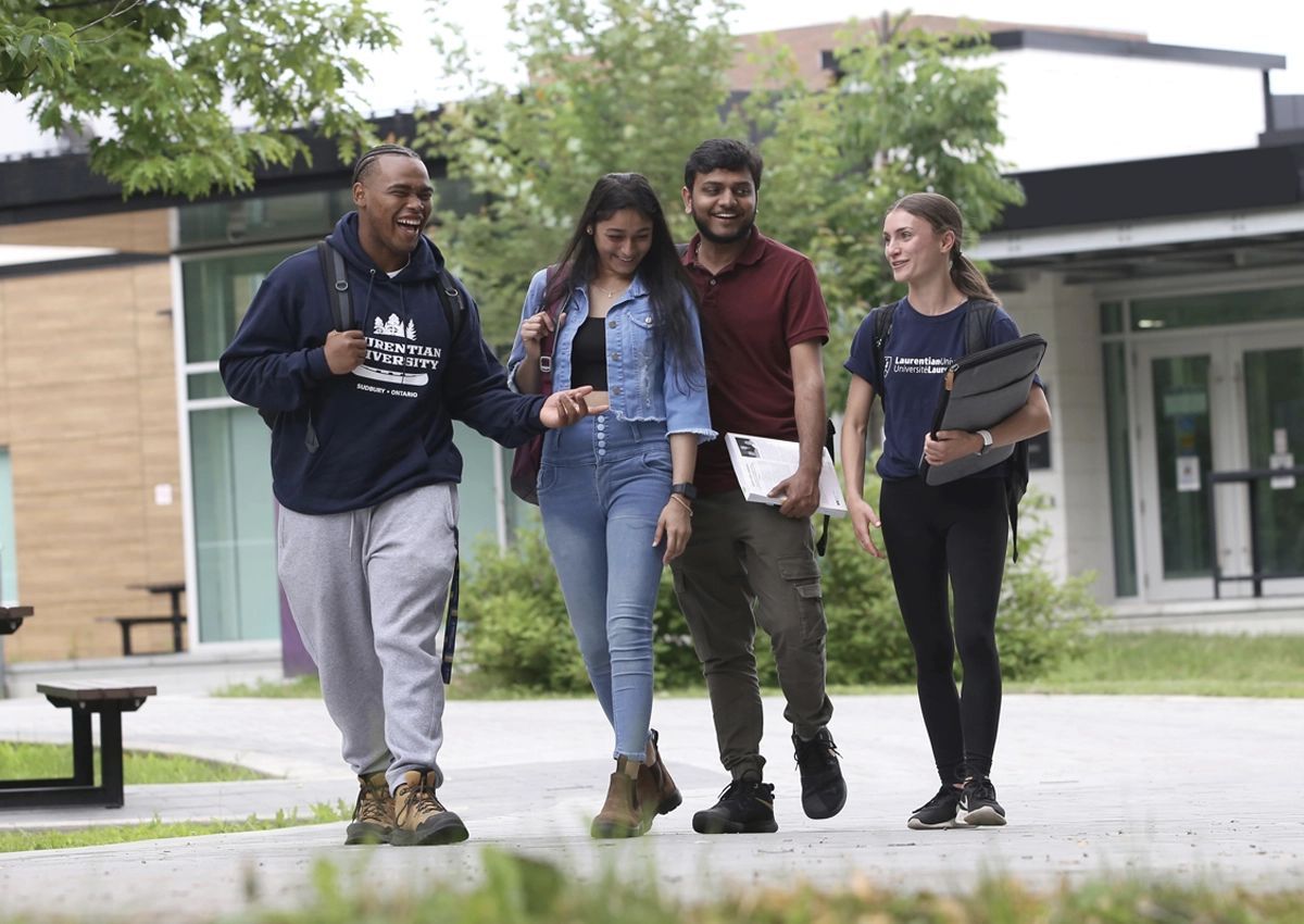 Group of students walking outside, smiling and laughing.