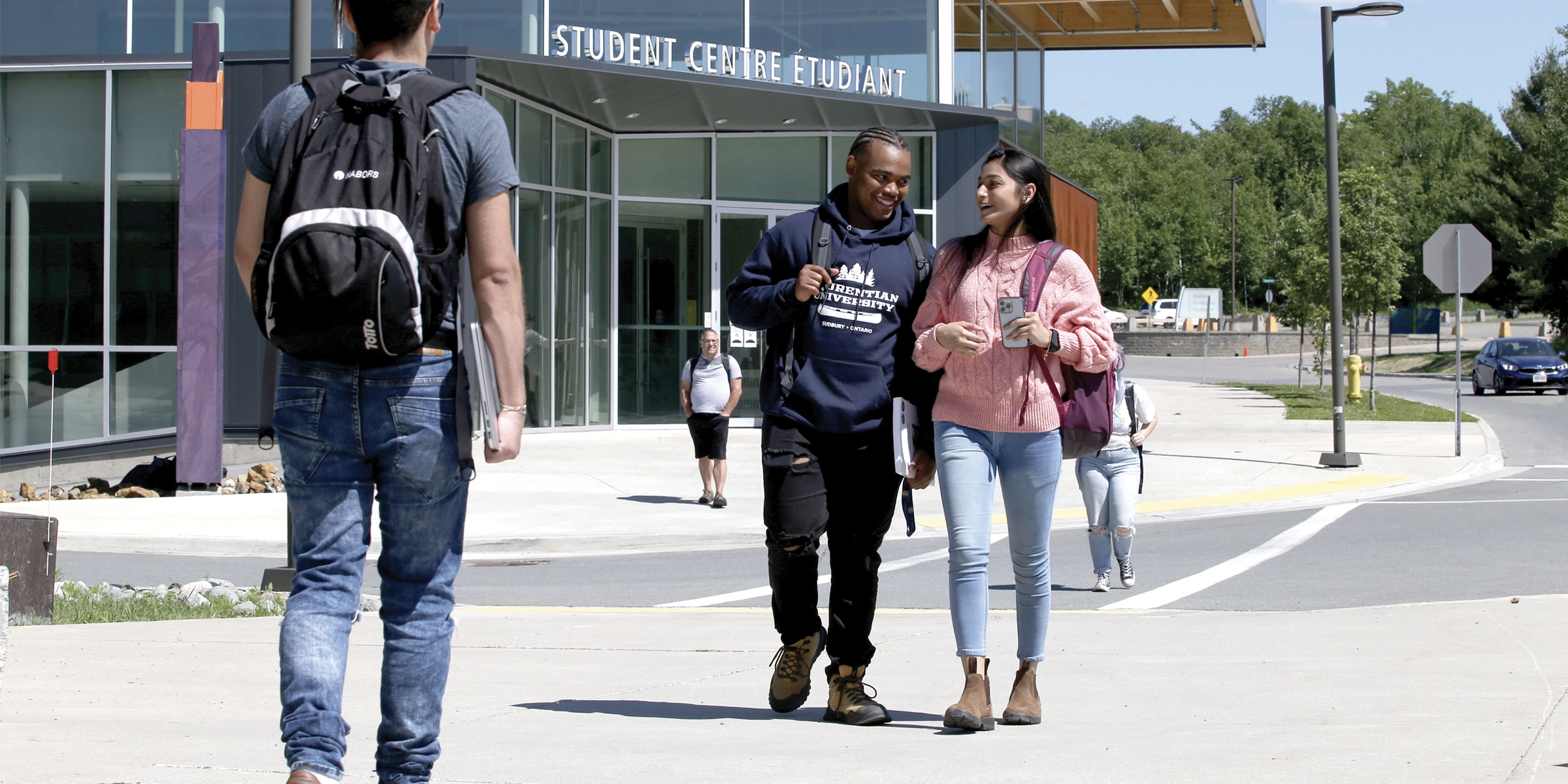Deux étudiants marchant devant le Centre étudiant de l'Université Laurentienne.