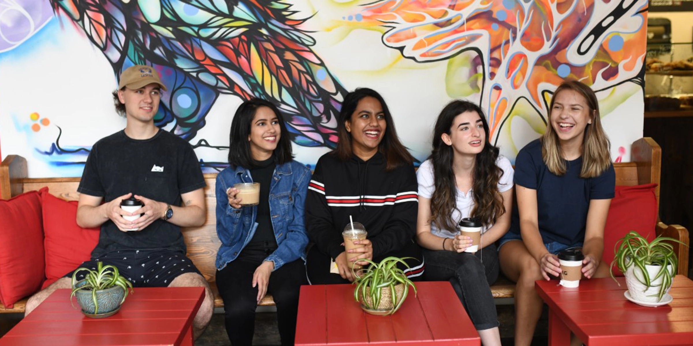 Un groupe d'étudiants assis sur un canapé avec leurs boissons provenant d'un café local.