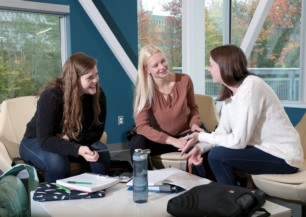 Trois étudiants en pleine discussion, assis dans l'Espace d'innovation et de commercialisation Jim-Fielding.