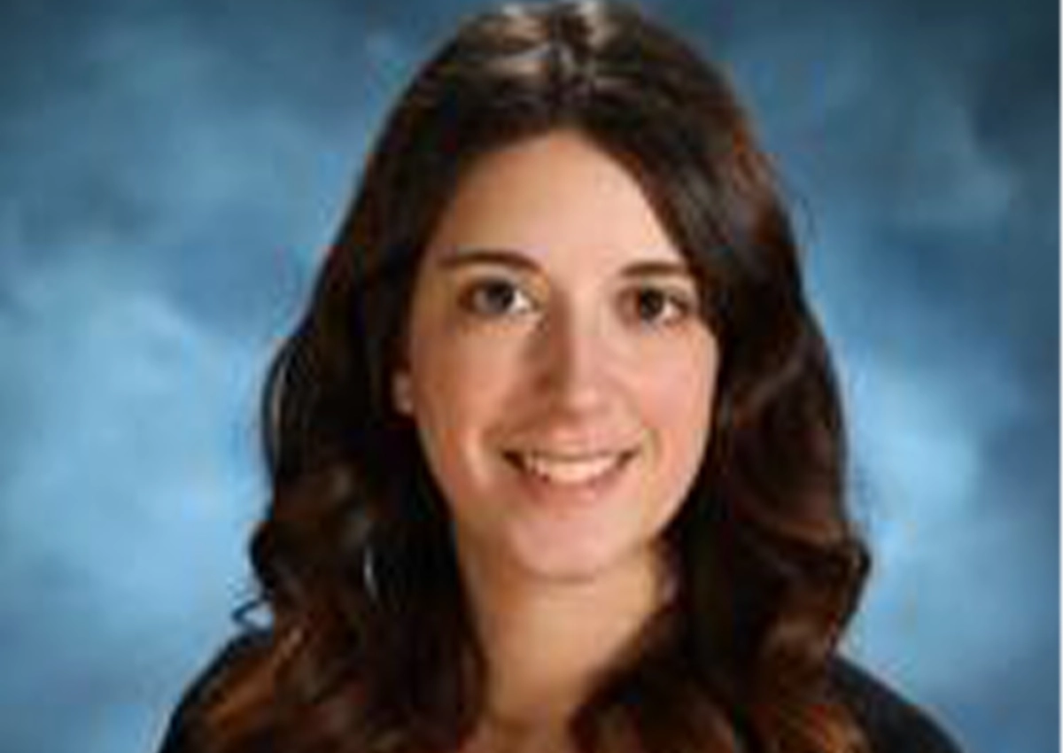 Dana Ellis's headshot. she is smiling at the camera with a blue backdrop behind her