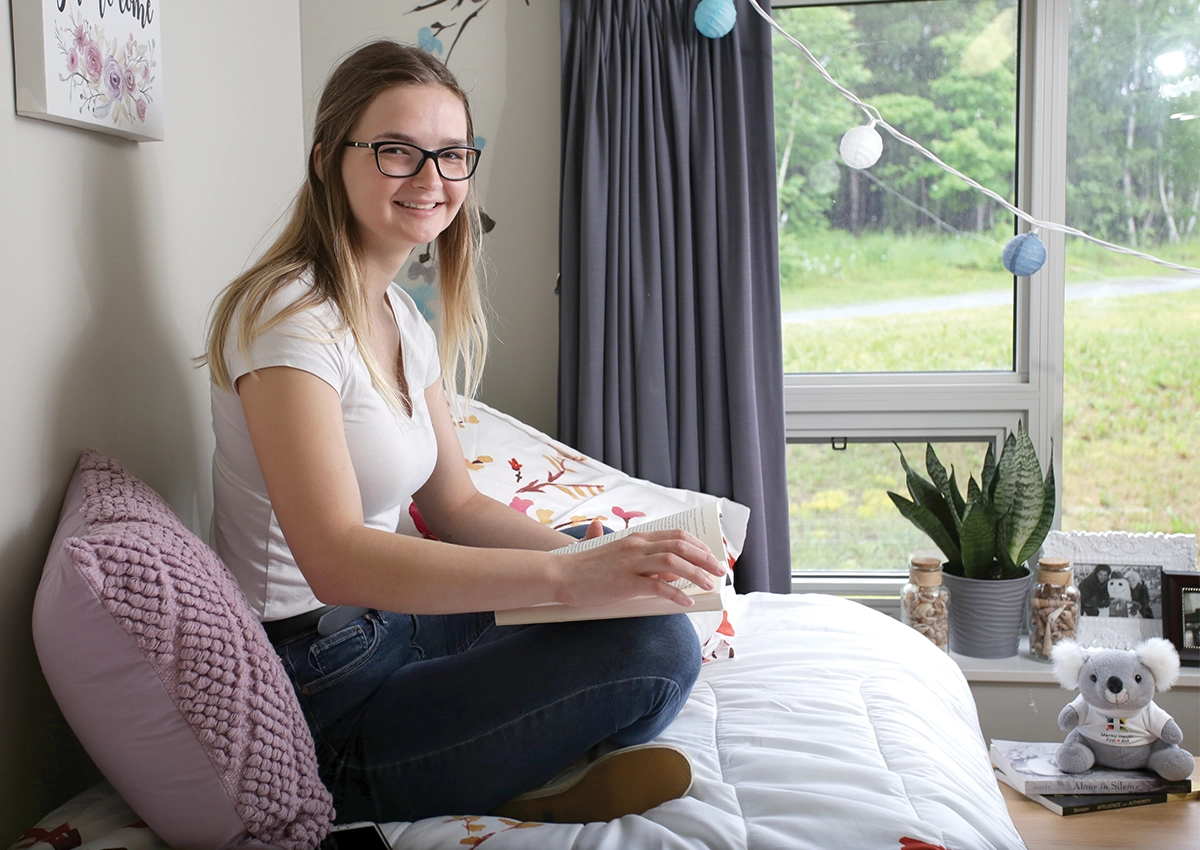 A Laurentian University student reading a book in her residence dorm.
