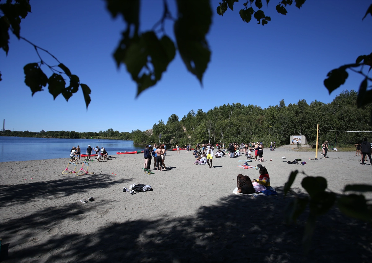 Students gathered on the Laurentian beach, with canoes lining the shore of Lake Nepahwin.