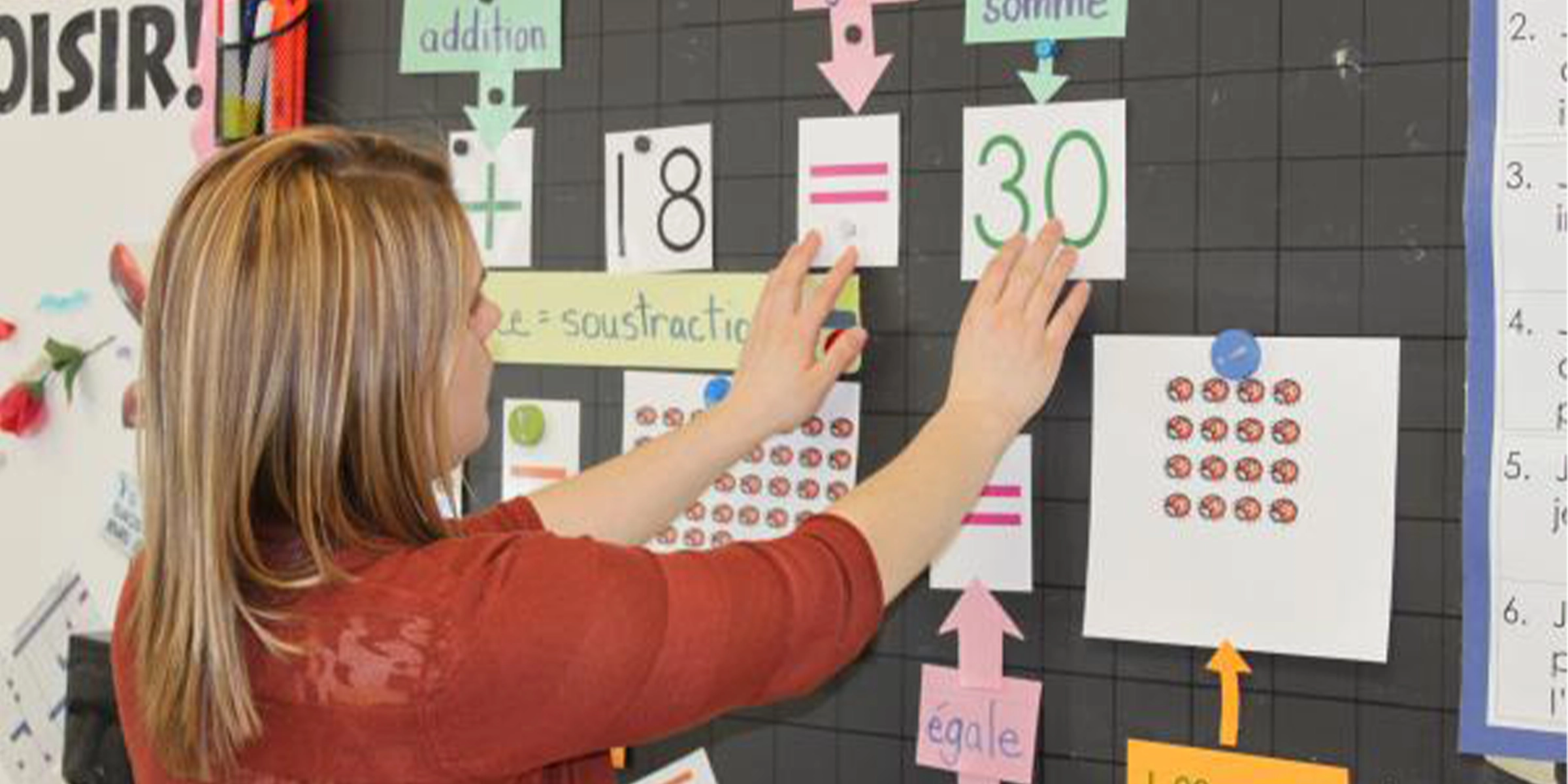 Une enseignante réorganise le tableau d'affichage dans sa classe. 