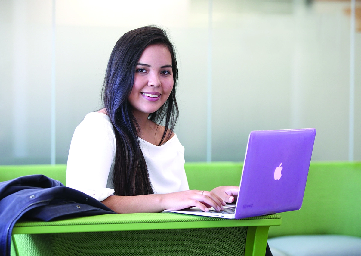 Un étudiant souriant alors qu'il utilise son ordinateur portable.