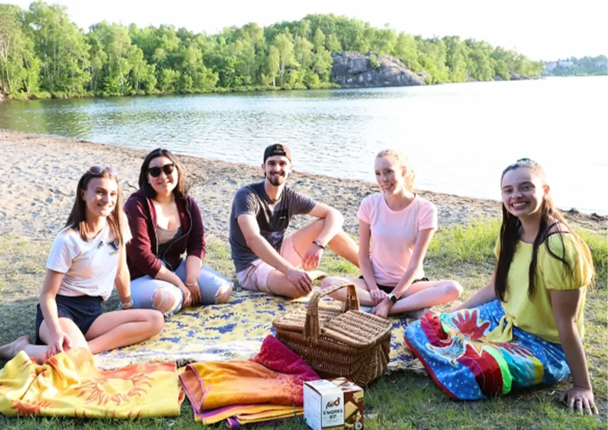 Un groupe d'étudiants de l'Université Laurentienne assis près du lac Nepahwin, à la plage Laurentienne.