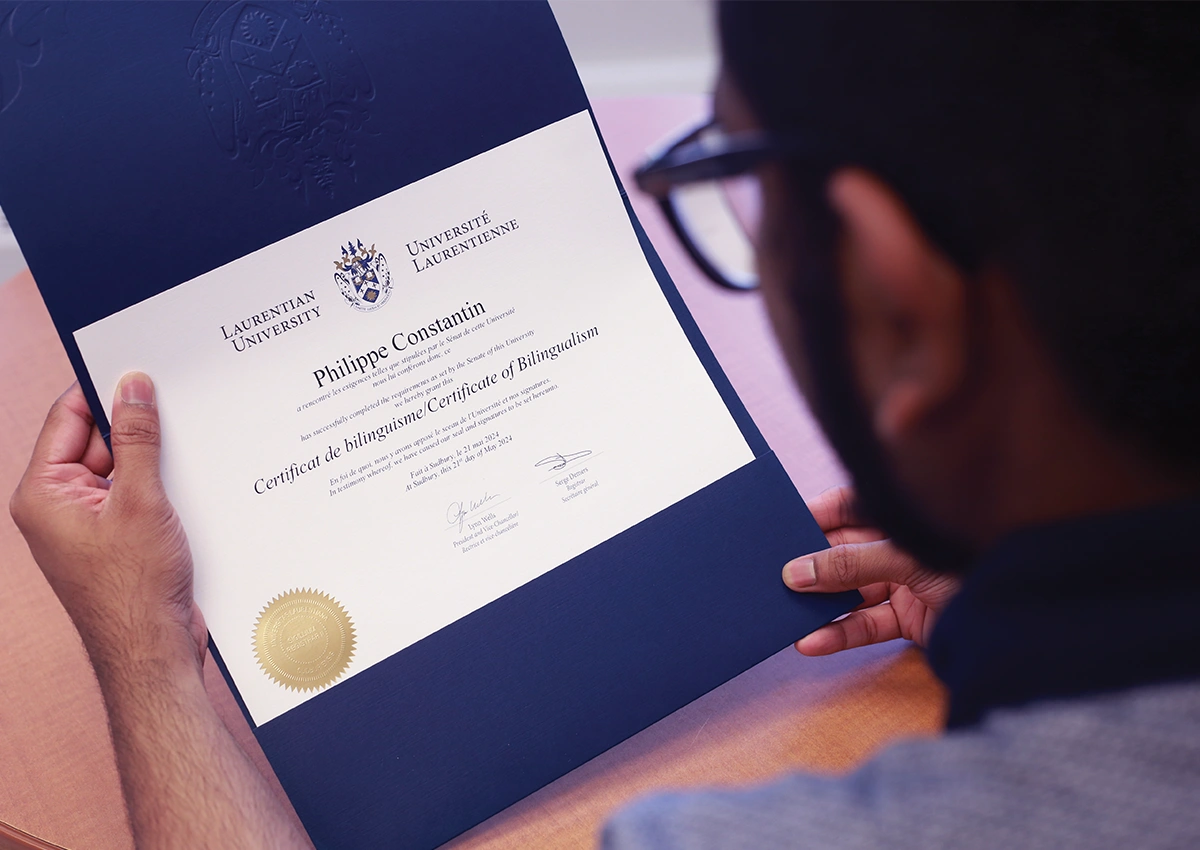 A Laurentian University student holding a Certificate of Bilingualism.