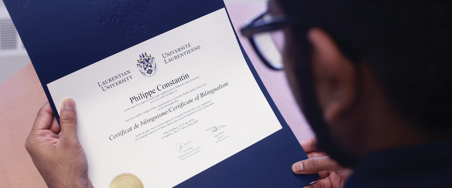 A student looking at his Certificate of Bilingualism from Laurentian University.