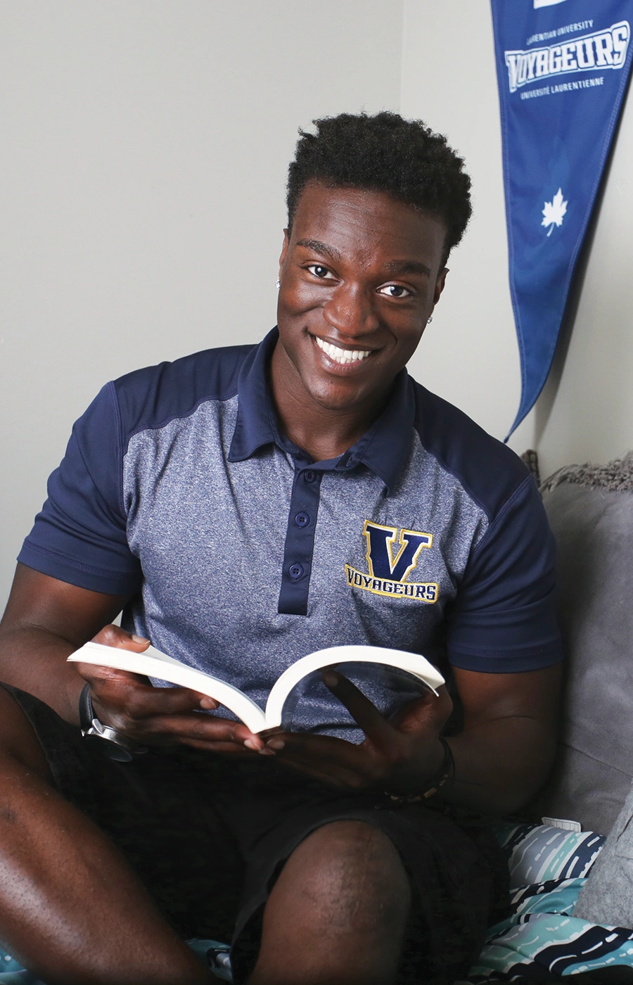 A Laurentian University student reading a book in his residence room.