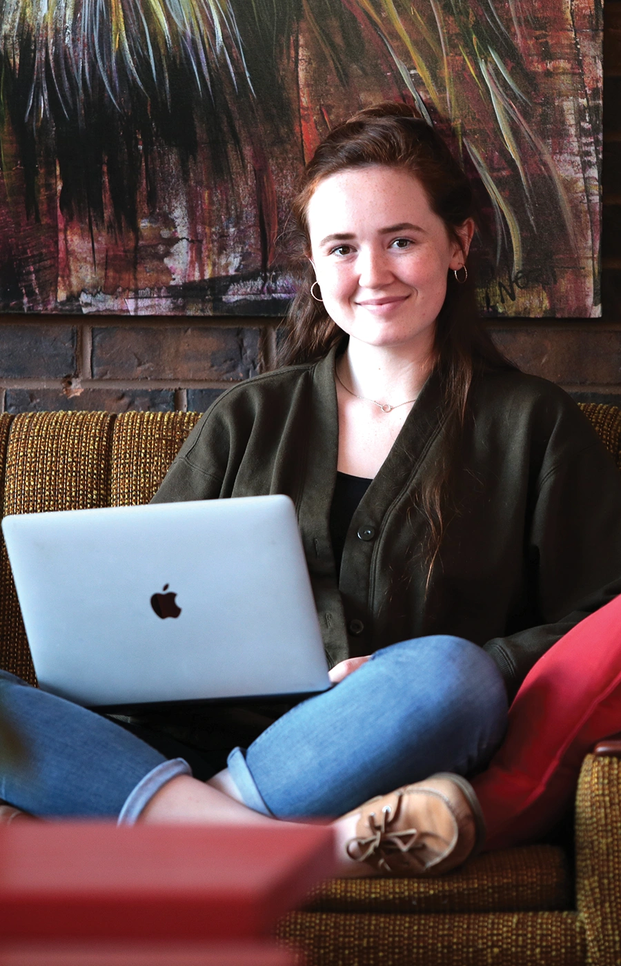 A Laurentian University student sitting o a couch with her laptop/