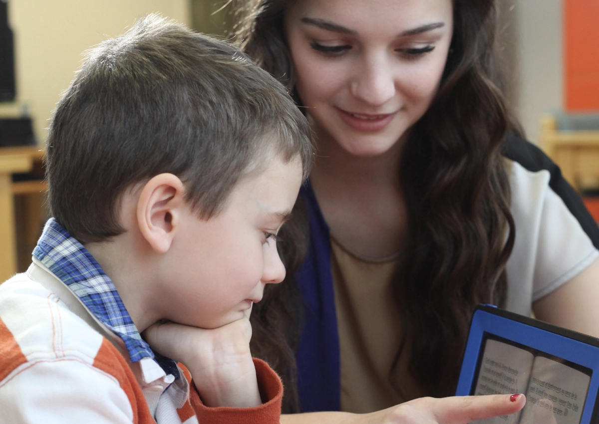 Une étudiante en orthophonie aide un jeune patient à améliorer sa prononciation à l'aide d'un iPad.