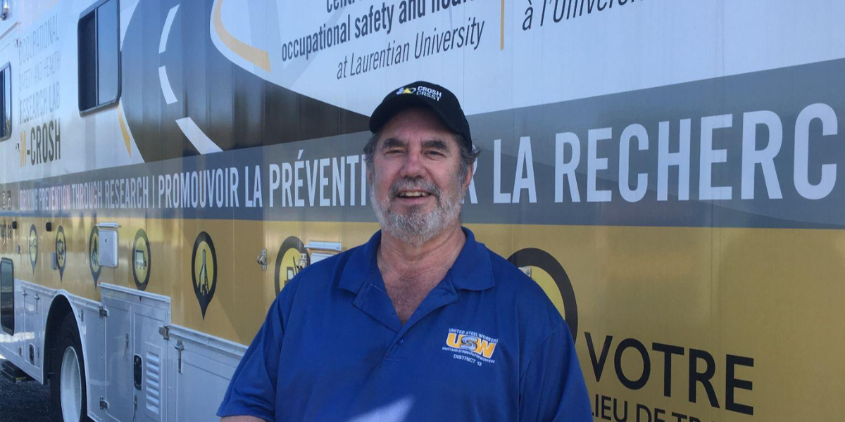 Dr. Leo Gerard smiling outdoors, standing in front of a CROSH-branded truck.