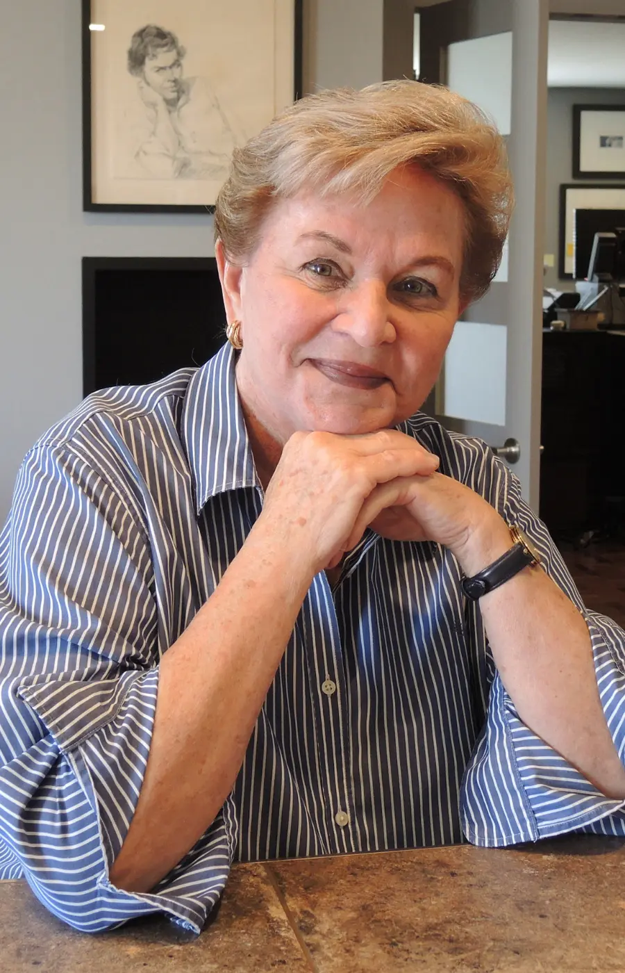 Posed portrait of Senator Marie-Paule Charette-Poulin sitting with her hands gently tucked under her chin, looking toward the camera.