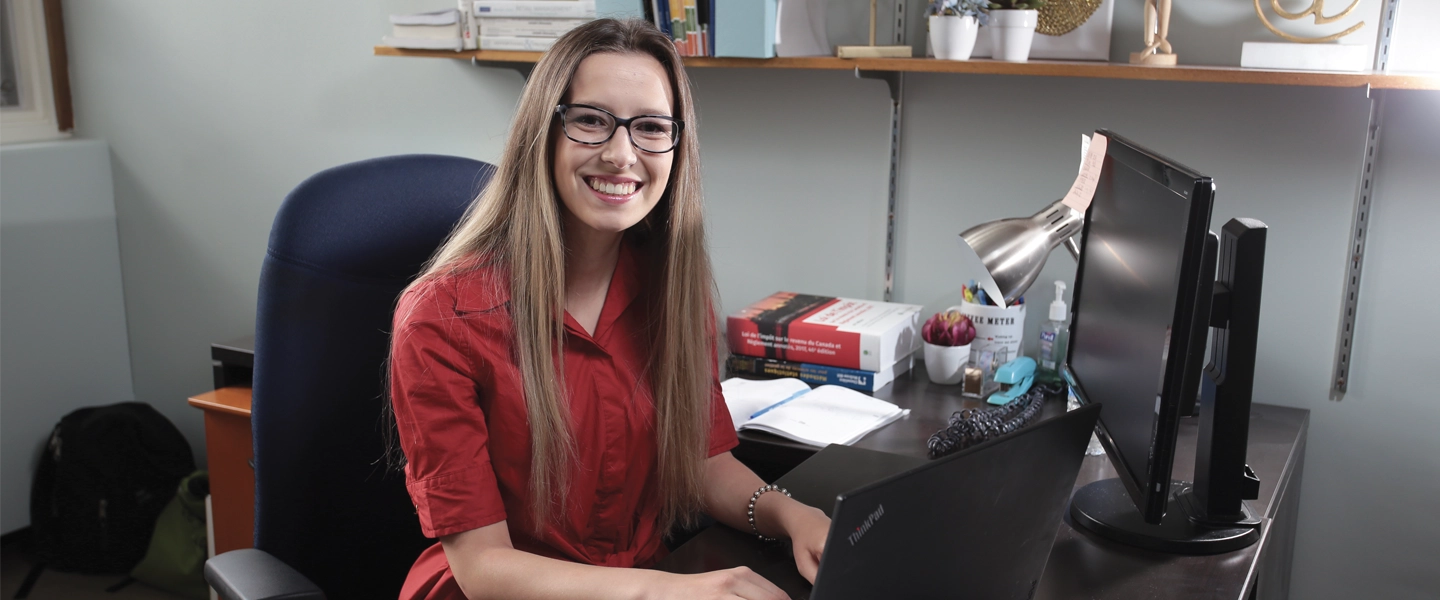 A woman smiling, working at a desk.