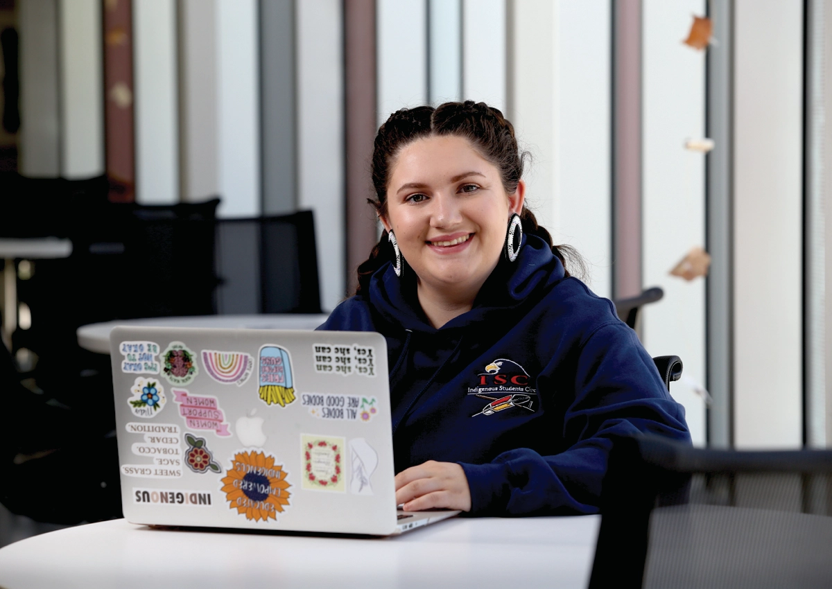 An Indigenous Laurentian University student on her laptop in the Indigenous Sharing and Learning Centre.