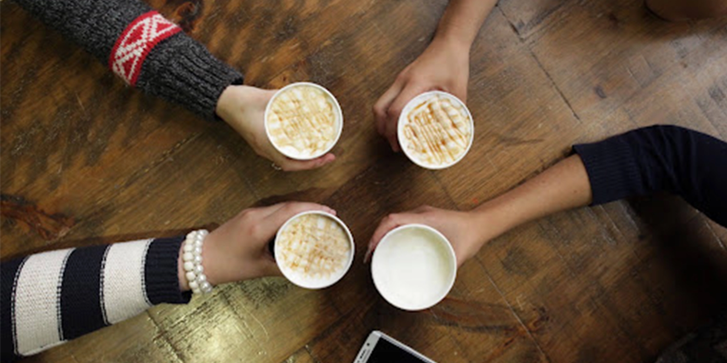 Camera looking down on 4 coffee mugs being held close together