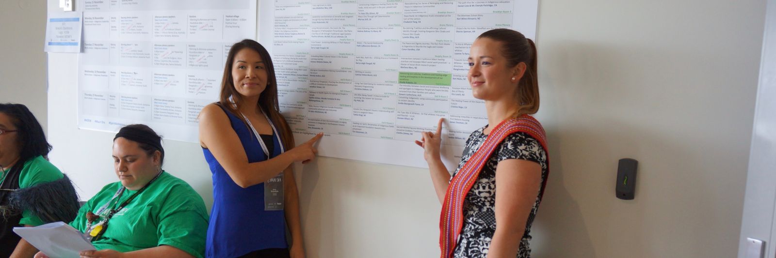 A teacher and a student pointing at a poster on the wall