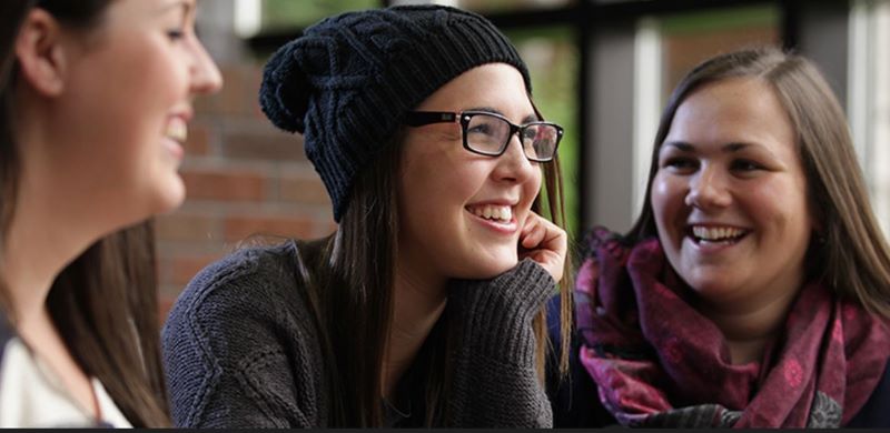 Three students sitting at a table discussing and contemplating their next steps.