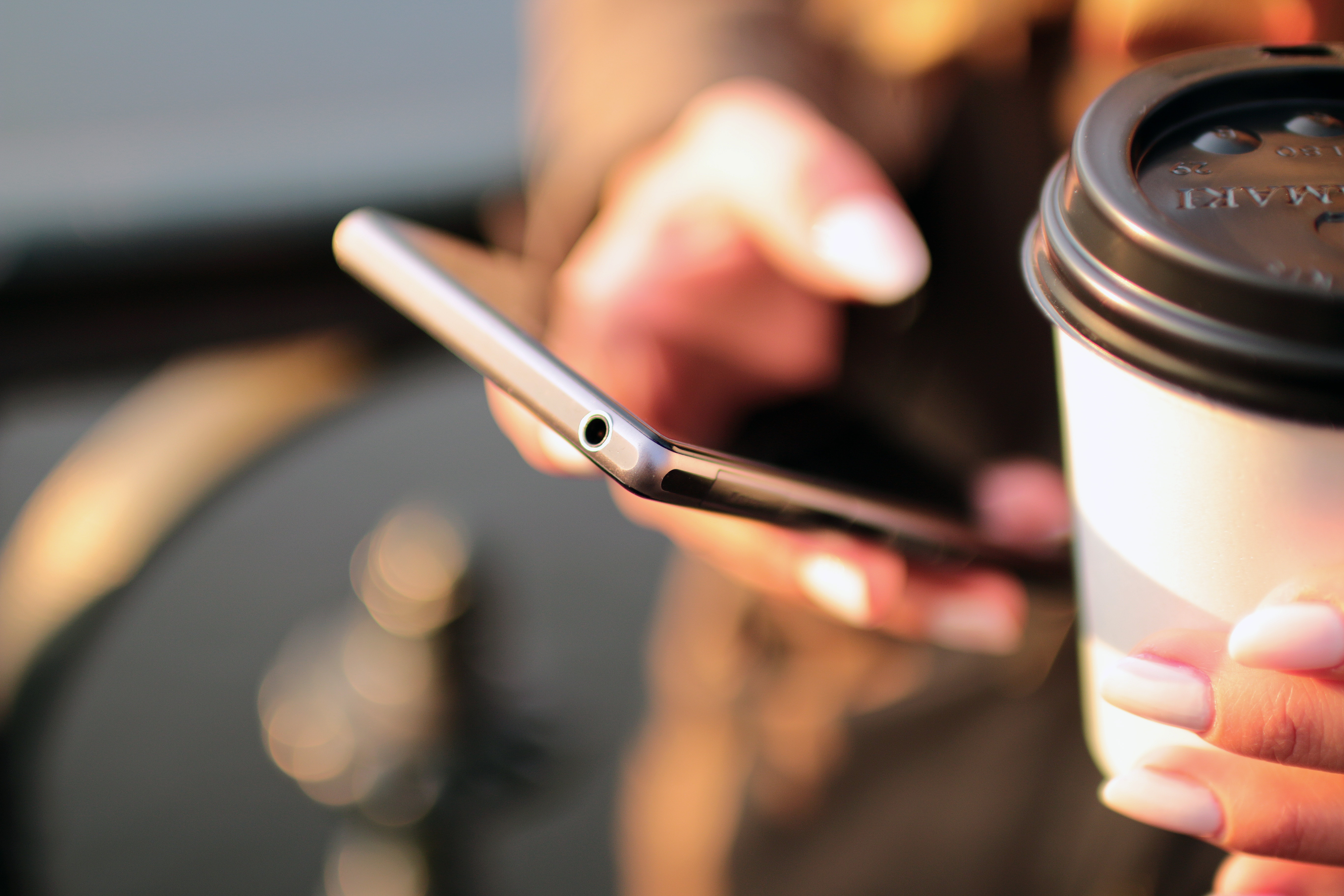 Holding a smartphone and coffee