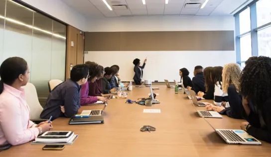 People sitting in a board room listening to a presenter.