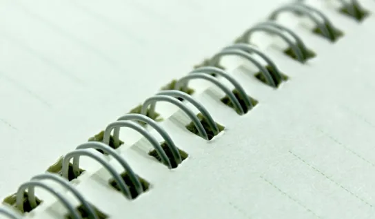 A close-up of an open spiral-bound notebook.