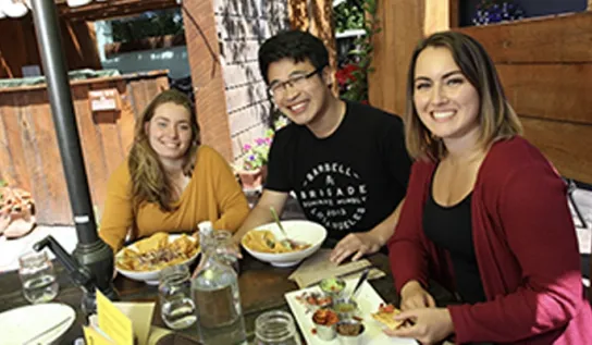 A group of three students eat at a local restaurant.
