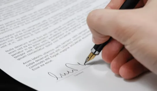 A close-up of someone signing a document.