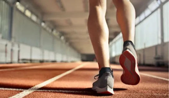 Une personne filmée à partir des cuisses en train de courir sur une piste d'athlétisme.