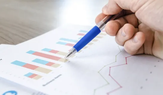Person reviewing graphs of data on a printed paper.