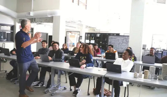 A professor teaching a lecture while students listen and take notes.