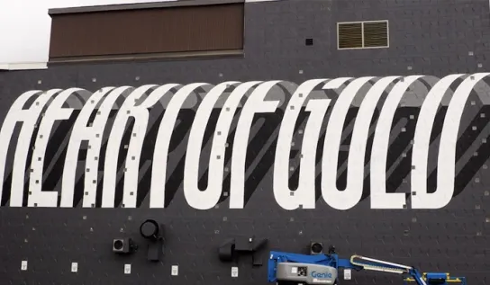 The side of a building painted black with "heart of gold" painted in white capital letters.
