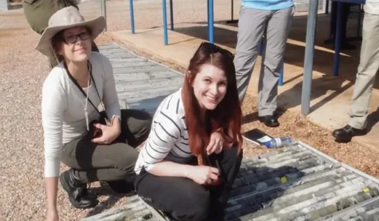 Two Earth Science students working outside, smiling.