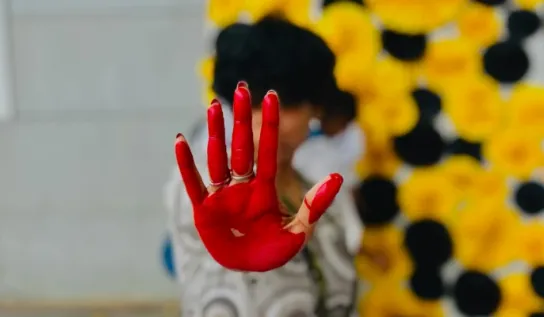 Indiginous woman holding up a hand covered with red paint