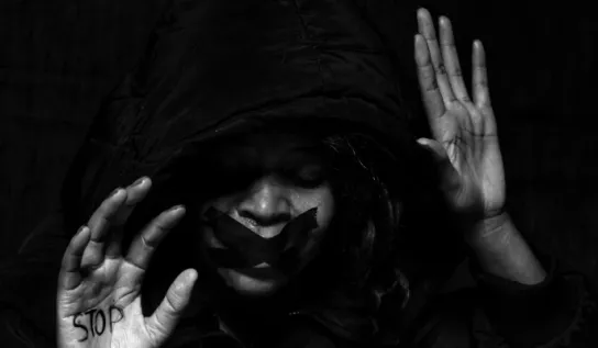 Woman with tape over her mouth with stop written on her palm