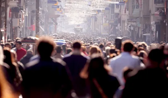 A crowd of people walking in a city.