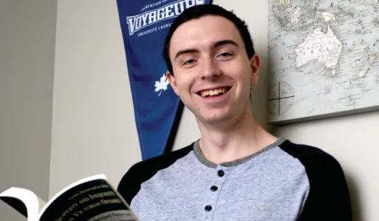Un étudiant de l'Université Laurentienne en train de lire un livre dans sa chambre en résidence.